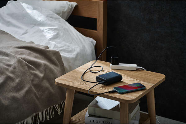 枕もとでコンセントをさしながらモバイルバッテリーで携帯を充電する様子
